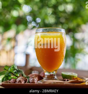 Un bicchiere di Jamu 'Kunir Asam', medicina tradizionale indonesiana delle erbe toniche. Servito con lime. Bali, Indonesia. Vista laterale. Immagine quadrata. Foto Stock