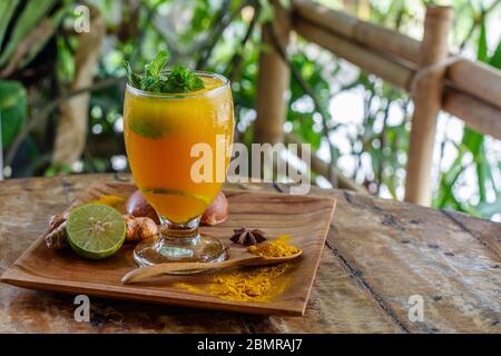 Un bicchiere di Jamu, tradizionale medicina tonica alle erbe indonesiana. Servito con menta e lime. Bali, Indonesia. Con spazio. Foto Stock