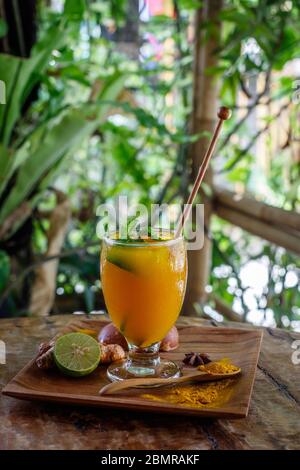 Un bicchiere di Jamu, tradizionale medicina tonica alle erbe indonesiana. Servito con menta e lime. Bali, Indonesia. Immagine verticale. Vista laterale. Con spazio. Foto Stock