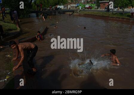 Lahore, Pakistan. 10 maggio 2020. Il giovane pakistano si gode il bagno nell'acqua del canale per battere il caldo e ottenere un certo sollievo dal tempo caldo a Ramazan-ul-Mubarak a Lahore. (Foto di Rana Sadid Hussain/Pacific Press) Credit: Pacific Press Agency/Alamy Live News Foto Stock