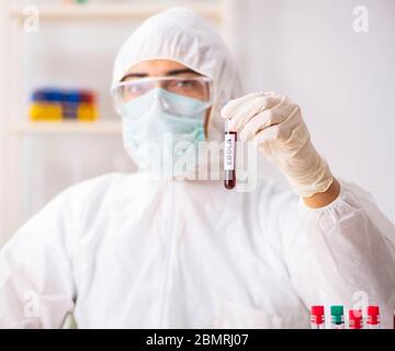 Il giovane bello assistente di laboratorio test di campioni di sangue in ospedale Foto Stock