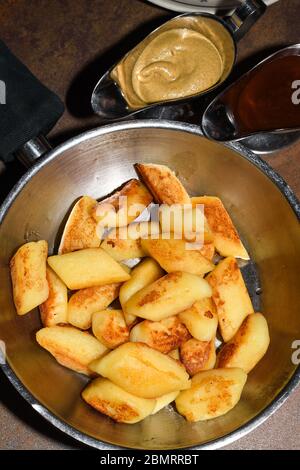 Gnocchi di patate fritti serviti in una padella con salsicce, cipolla fritta, salsa al formaggio. Ristorante con tavolo, concetto di cena polacca Foto Stock