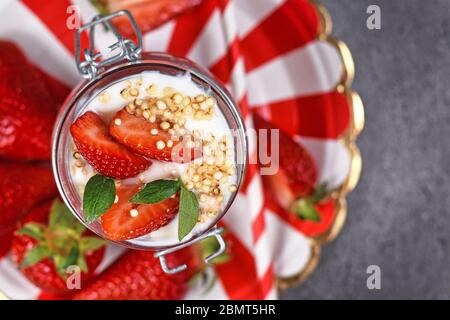 Vista dall'alto del dessert alla fragola con yogurt e cereali di quinoa soffrigati su piatti a righe rosse e bianche Foto Stock