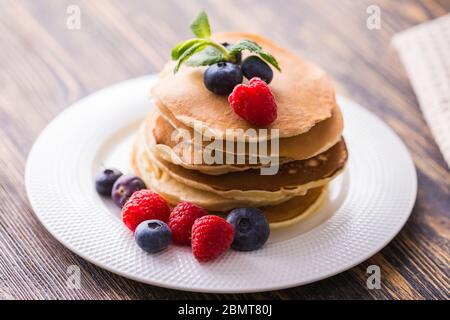 Pancake con mirtilli e lampone su sfondo di legno. Colazione e pasto tradizionale. Foto Stock