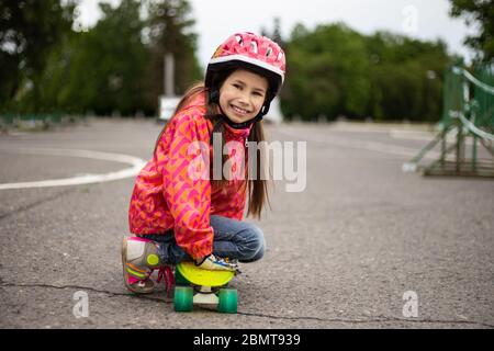 Carina ragazza teenager che indossa il casco a cavallo su uno skateboard in bellissimo parco estivo Foto Stock