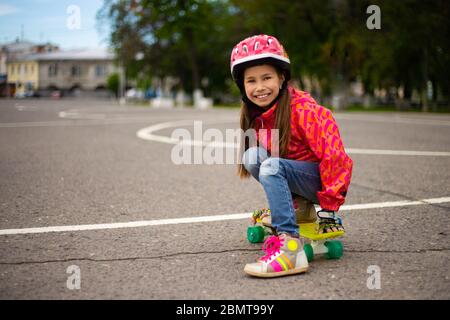 Carina ragazza teenager che indossa il casco a cavallo su uno skateboard in bellissimo parco estivo Foto Stock