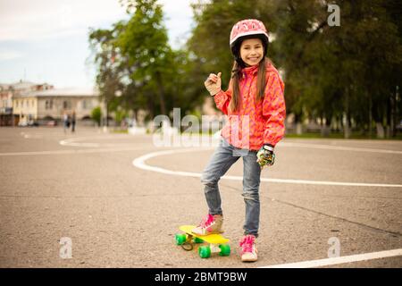 Carina ragazza teenager che indossa il casco a cavallo su uno skateboard in bellissimo parco estivo Foto Stock