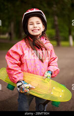 Carina ragazza teenager che indossa il casco a cavallo su uno skateboard in bellissimo parco estivo Foto Stock