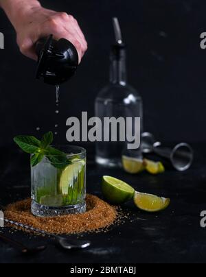 bevanda alcolica con soda, lime e menta, su sfondo scuro. home bar Foto Stock