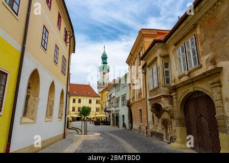 Stretta strada medievale di Sopron con la torre di avvistamento dei vigili del fuoco sullo sfondo Foto Stock