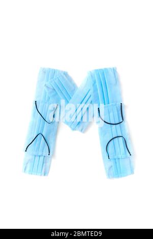 Lettera M realizzata con maschere mediche protettive su sfondo bianco. Foto Stock