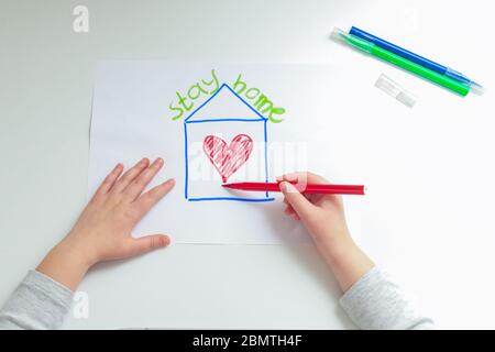 Vista dall'alto del cuore di disegno mano del bambino in casa dipinta con penna a punta di feltro su carta bianca a casa. Concetto di soggiorno a casa. Foto Stock