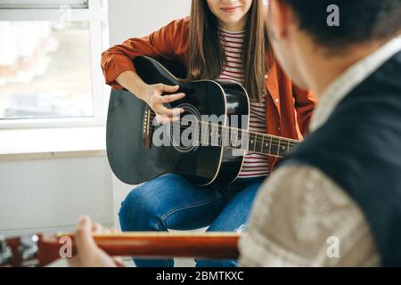 Imparare a suonare la chitarra. L'insegnante spiega allo studente le basi per suonare la chitarra. Lezioni individuali di scuola domestica o extracurricolare. Foto Stock