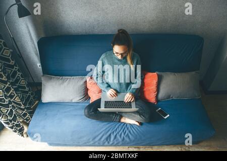 Ragazza che lavora su un computer portatile da casa o studente che studia da casa o da freelancer. Oppure sta guardando un video o utilizzando Internet Foto Stock