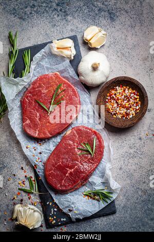 Filetto di manzo crudo su un ardesia con spezie. Carne cruda di manzo bistecche sfondo. Foto Stock