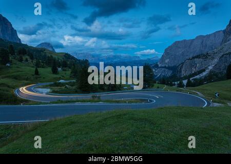 Auto trail luci sul Passo Pordoi con sfondo di montagne al tramonto, Provincia Autonoma di Bolzano Alto Adige, Dolomiti italiane, Italia, Europa Foto Stock