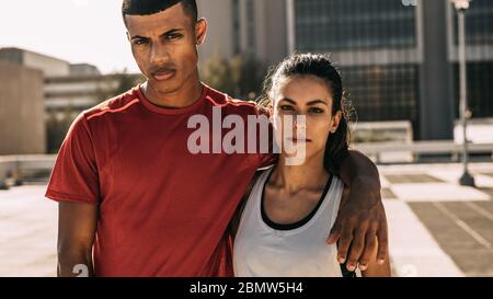 Coppia fitness in città per allenarsi di mattina. Uomo e donna in abbigliamento sportivo che si stanno guardando insieme la fotocamera. Foto Stock