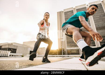 Allenati uomini e donne all'aperto in città. Coppia durante esercizi di allenamento in città. Foto Stock