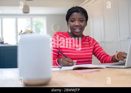 Adolescente ragazza fare esercitazioni a casa fare domande Digital Assistant Foto Stock