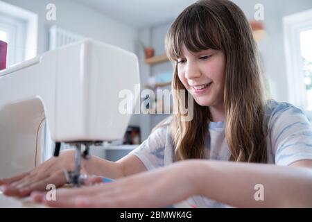 Giovane ragazza imparare come usare la macchina da cucire a casa Foto Stock