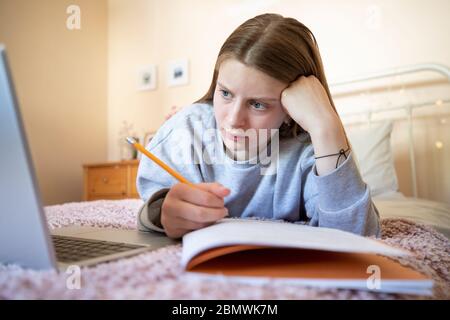 Adolescente femminile stressato che ha problemi con l'uso del laptop per le esercitazioni o la scuola domestica Foto Stock