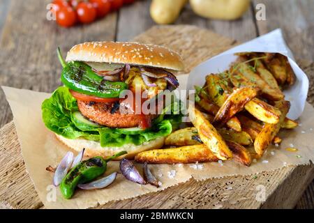 Cibo da strada senza carne - delizioso hamburger vegetariano con patatine di soia e verdure alla griglia, servito con zeppe di patate Foto Stock