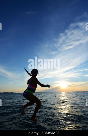 Una ragazza che salta nel mare Adriatico dalla passeggiata a Zara, Croazia. Foto Stock