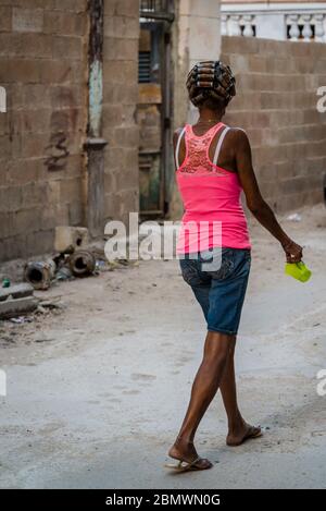 Donna con i suoi capelli arricciatori camminare in una strada, quartiere Havana Centro, Havana, Cuba Foto Stock