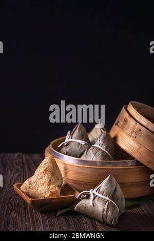 Zongzi - zongzi gnocchi di riso cinese in un vaporetto su tavolo di legno sfondo nero retro per la festa Dragon Boat Festival, primo piano, spazio copia. Foto Stock