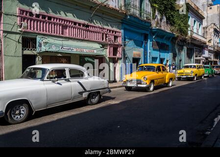 Auto d'epoca che percorrono la famosa via Neptuno, il quartiere Havana Centro, l'Avana, Cuba Foto Stock