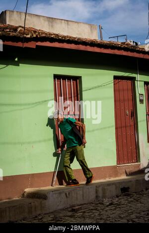 Uomo locale con un bastone a piedi nel centro dell'era coloniale della città, Trinidad, Cuba Foto Stock