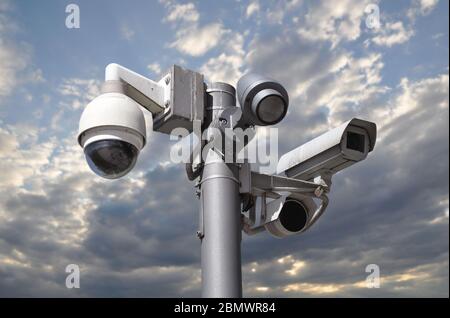 Telecamere CCTV su un'unica asta contro un cielo blu nuvoloso. Foto Stock