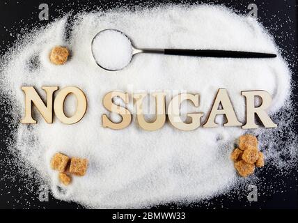 Non c'è testo di zucchero dalle lettere, lo zucchero scivola su un cucchiaio, suggerendo un concetto di dieta e salute. Foto Stock