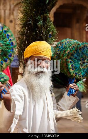 JAISALMER, India - 14 Marzo 2015: il vecchio uomo in turbante giallo vende penne di pavone nella città di Jaisalmer, India. Jaisalmer è una meta molto popolare tra i turisti desti Foto Stock