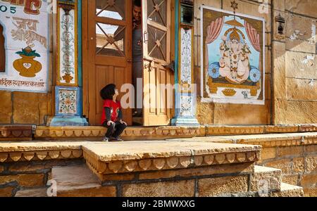 JAISALMER, India - 14 Marzo 2015: il giovane ragazzo è guardando al suo padre nella porta alla vecchia casa in città di Jaisalmer, India. Jaisalmer è una meta molto popolare tra i t Foto Stock