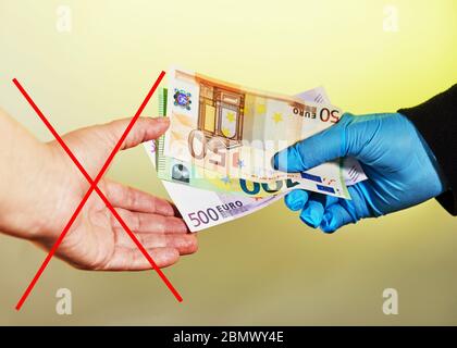 Mano di un uomo in un guanto medico blu dà soldi a una donna senza un guanto sotto forma di euro Notes.IT è vietato prendere soldi senza Foto Stock