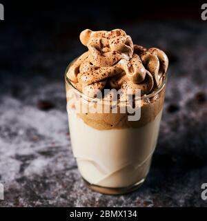 primo piano di un bicchiere di caffè dalgona su una superficie marmorizzata grigia Foto Stock