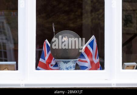 Wimbledon, Londra, Regno Unito. 11 maggio 2020. Decorazioni commemorative del VE Day adornano la finestra anteriore di una casa nel villaggio di Wimbledon, tra cui un casco Wardens RAID Air della seconda Guerra Mondiale. Credit: Malcolm Park/Alamy Live News. Foto Stock