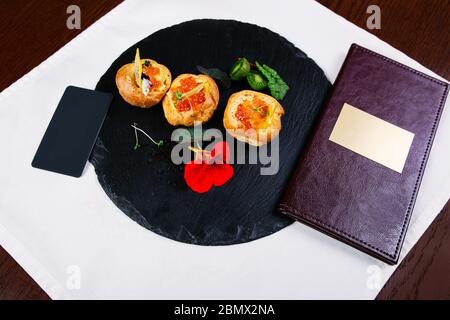 Salmone affumicato crostino panini con le uova di salmone o caviale su un nero ardesia bordo con prezzemolo fresco in foglie, fettine di limone e i capperi. Vista aerea Foto Stock