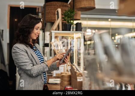 Giovane donna asiatica sorridente che usa un tablet nel suo negozio Foto Stock