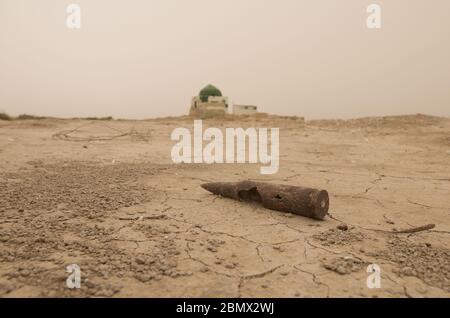 Una pallottola di grande calibro, probabilmente una reliquia degli anni '80 dalla guerra iraniana in Iraq, si trova su un letto di canna asciutto nel sud dell'Iraq. Le paludi furono deliberatamente prosciugate da Saddam Hussein dopo la prima guerra del Golfo del 1991 Foto Stock