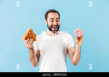 Immagine di giovane felice uomo positivo isolato su sfondo blu parete tenendo sandwich e ciambella. Foto Stock