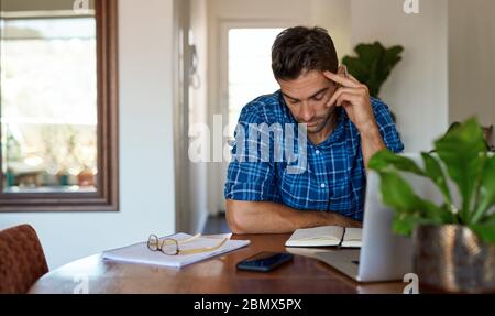 Giovane uomo che lavora da casa nel suo soggiorno Foto Stock