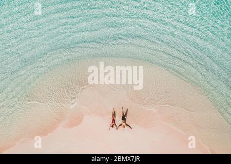Coppia adagiata sulla famosa spiaggia rosa nel parco nazionale di Komodo. Color menta turchese, acqua limpida, vacanze tropicali in luna di miele. Vista aerea del drone dall'alto. Foto Stock