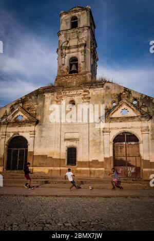 I bambini che giocano a calcio di fronte al derelict e hanno chiuso la Chiesa di Saint Ana, Trinidad, Cuba Foto Stock