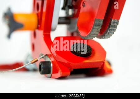 Primo piano di un meccanismo di bloccaggio rosso di un morsetto industriale di sollevamento su uno sfondo bianco Foto Stock