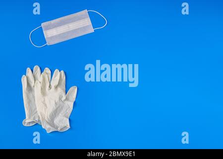 Kit di dispositivi di protezione individuale (PPE) contro il coronavirus con maschera facciale, set di guanti su sfondo blu con spazio per la copia per titolo o testo. Foto Stock