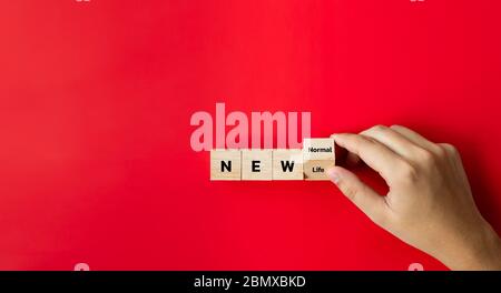 Mano tenere sopra ai dadi di legno e testo la parola 'nuovo normale' UNA nuova vita che non è mai accaduto prima e diventa normale dopo lo scoppio del Foto Stock