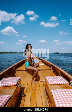 Giethoorn Olanda donna visitare il villaggio con una barca, vista del famoso villaggio con canali e case rustiche tetto di paglia in zona fattoria su un caldo Foto Stock