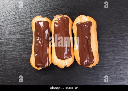 Deliziose leclairs di cioccolato su un tavolo nero. Foto Stock